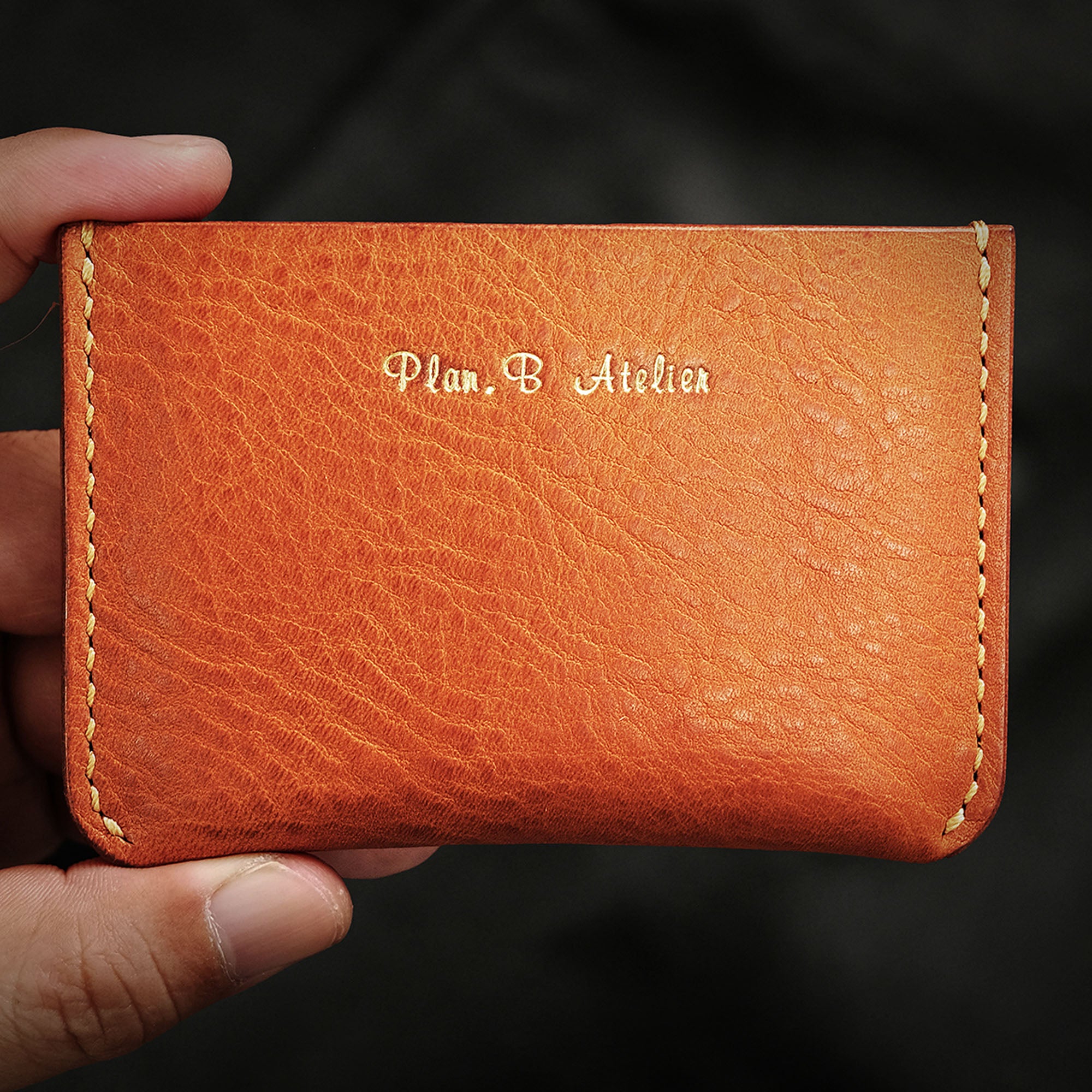 Front view of the Minimalist Wallet held between fingers, showcasing its compact size.