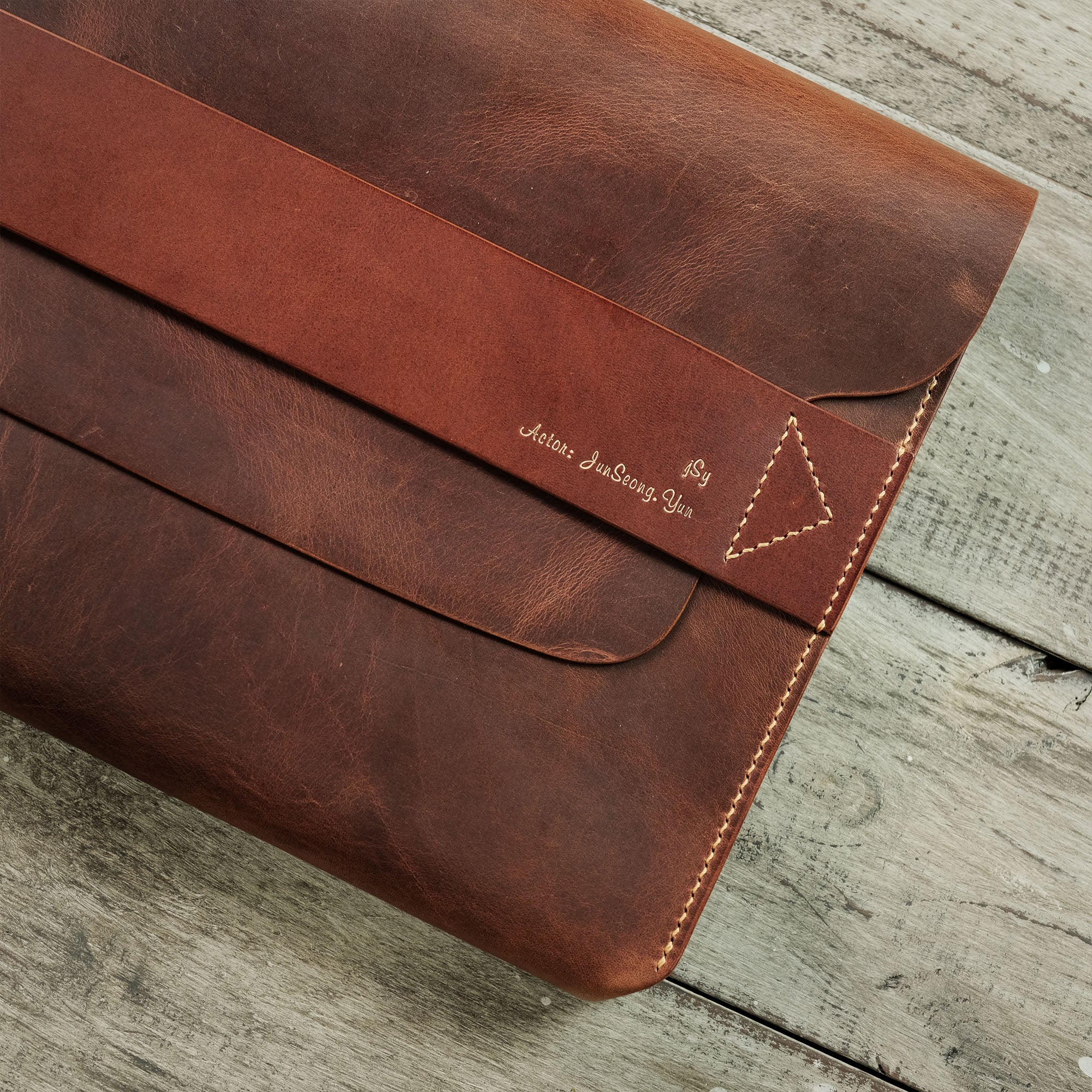 Close-up of the compact briefcase, showing the left half of the front with a focus on the flap and strap closure.