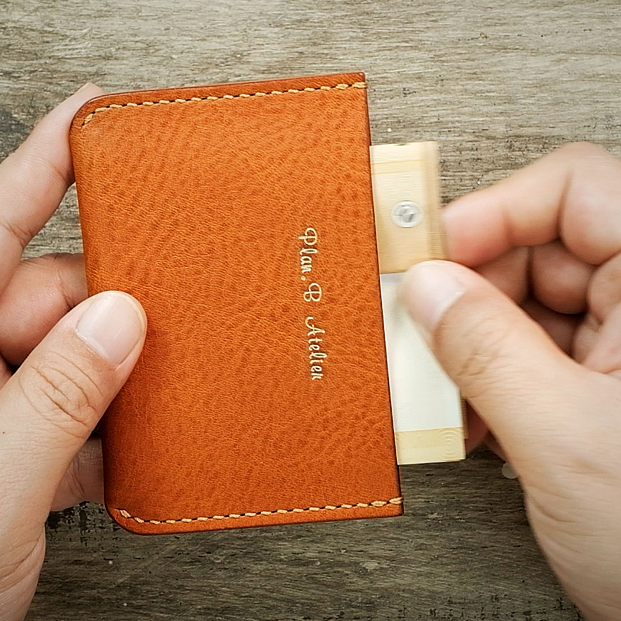 Close-up of cash being placed into the Minimalist Wallet, highlighting convenient storage access.