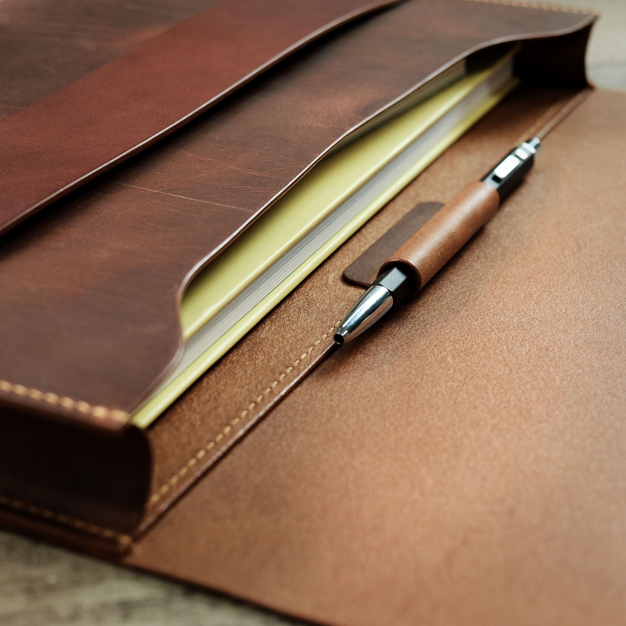 Interior view of the compact briefcase with a book stored inside and a pen secured in the pen loop.