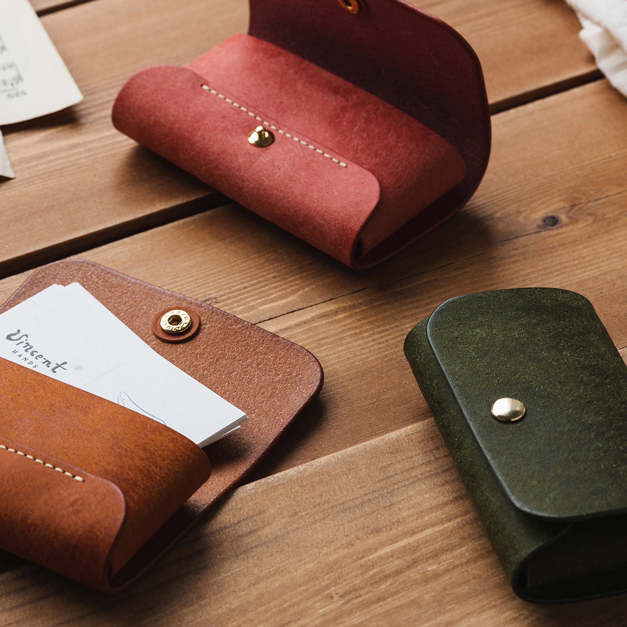 Angled view of three Business Card Wallets in brown, green, and pink, highlighting their minimalist structure.