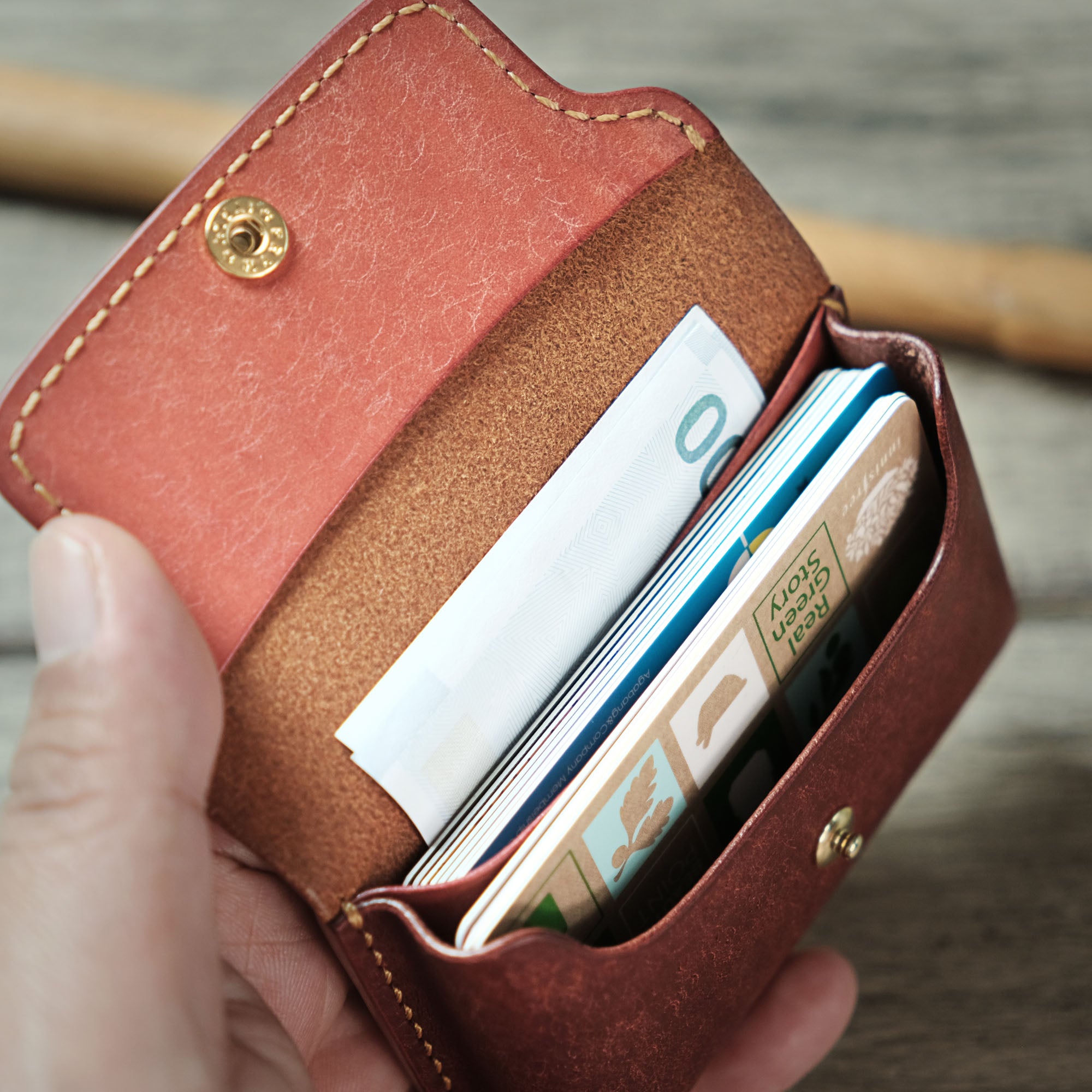 A hand inserting cards into the Compact Plump Wallet, highlighting its functional design.