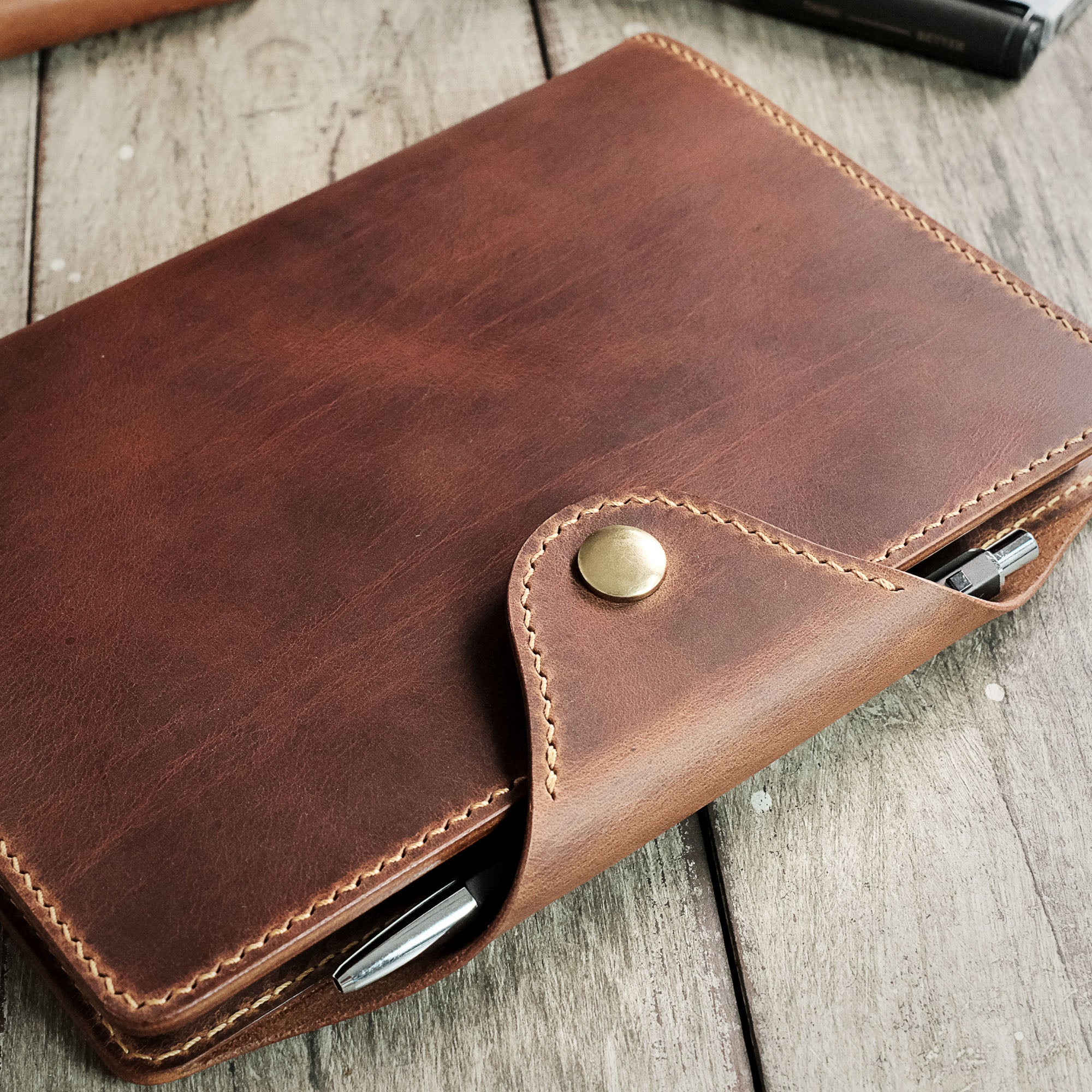 Close-up angled shot of the leather flap on the A5 Notebook Cover, highlighting the stitching details.